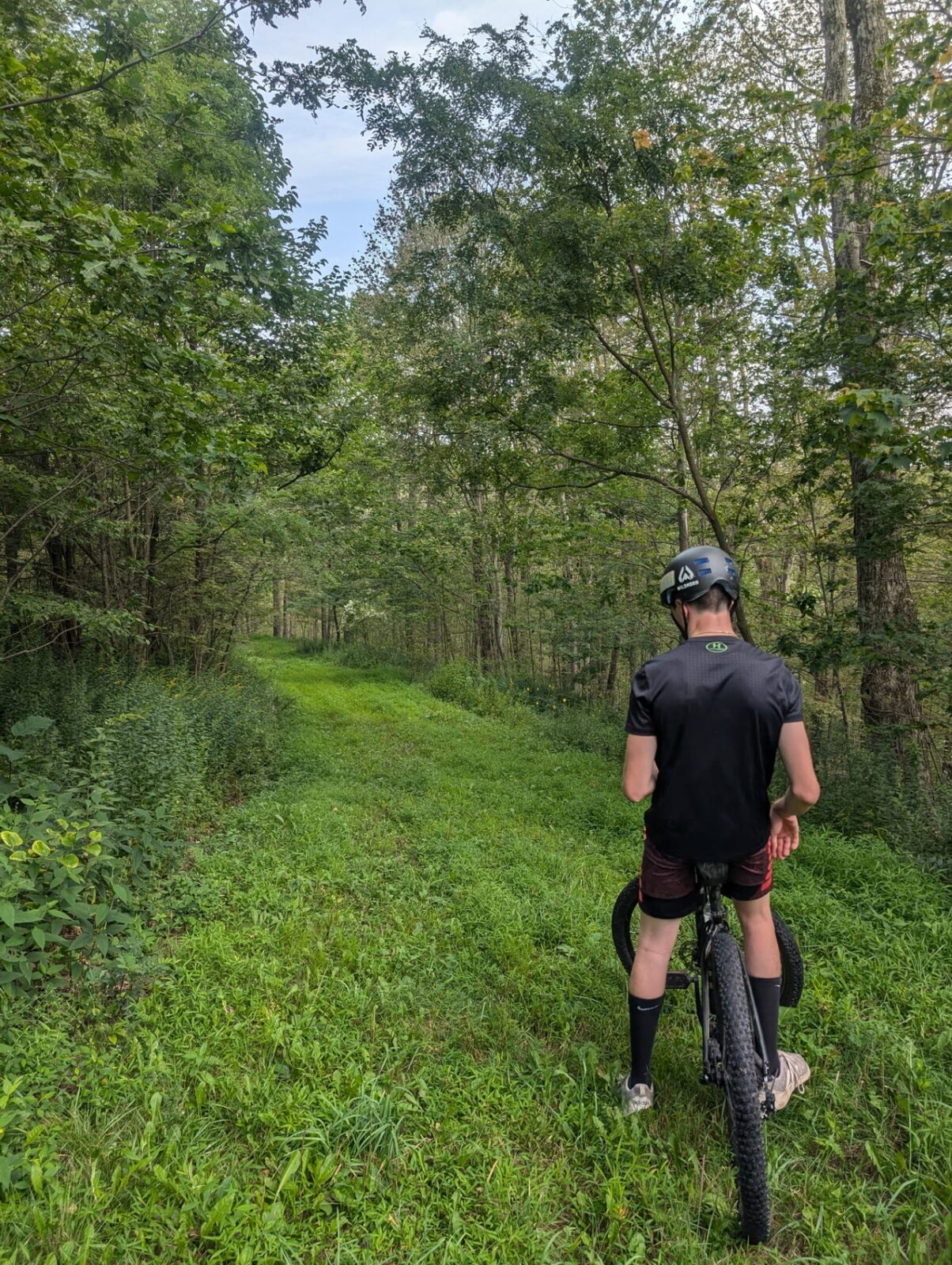 Dylan Steele, founder of Fern Mountain Rentals, with a mountain bike on a forest trail